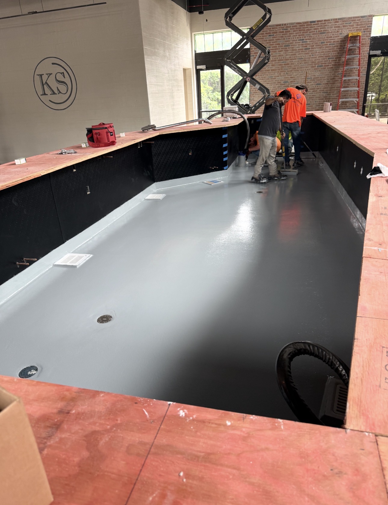Gray solid-color commercial floor coating being installed behind a service counter