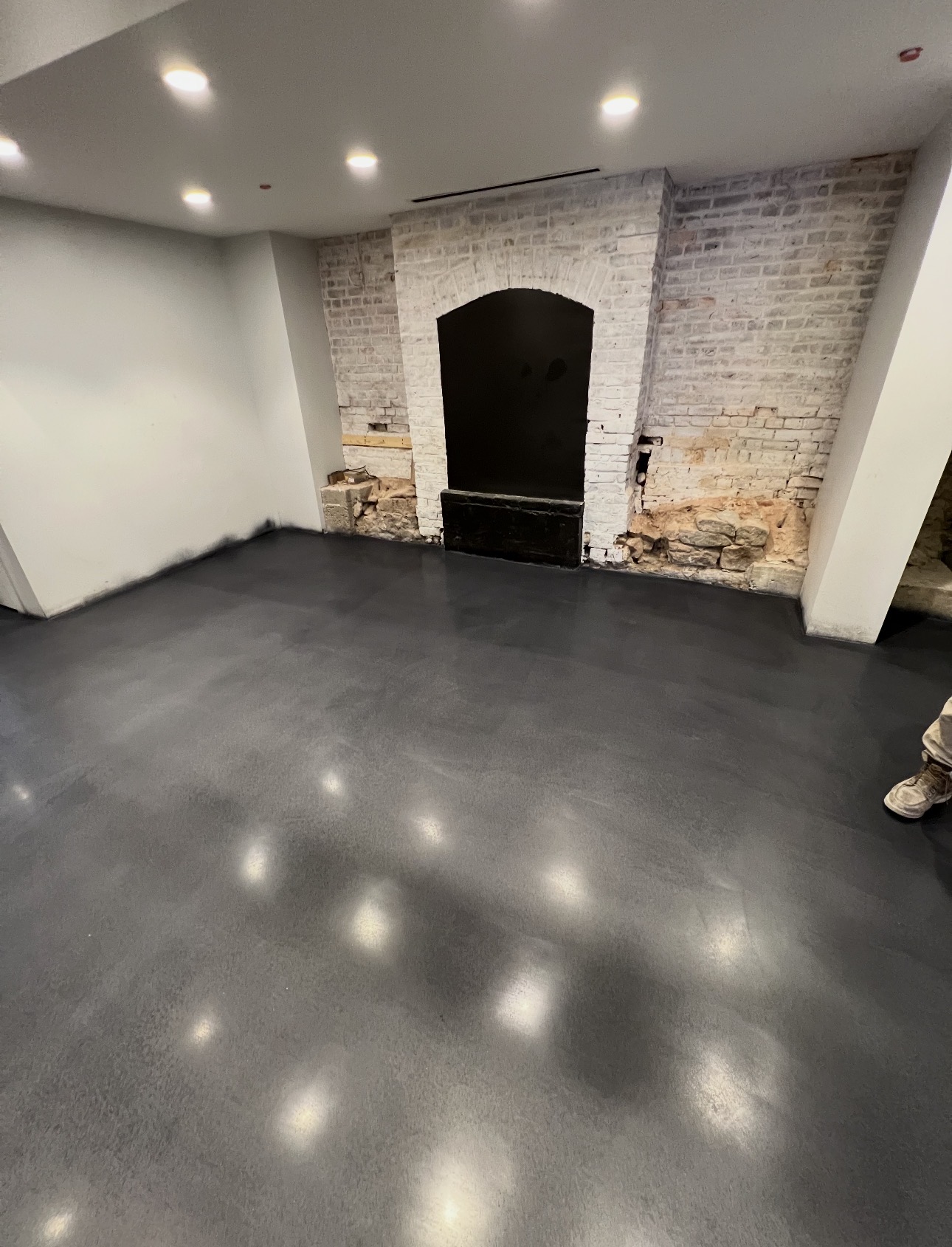 Charcoal sealed concrete floor in a finished basement with exposed brick