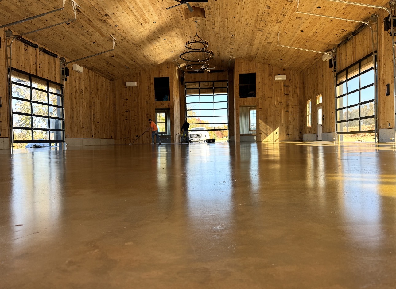 Wide amber sealed concrete floor in a wood event barn during final finishing
