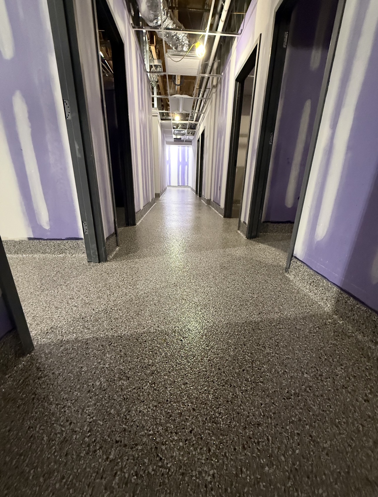 Gray full-broadcast flake epoxy floor and cove base in a commercial hallway