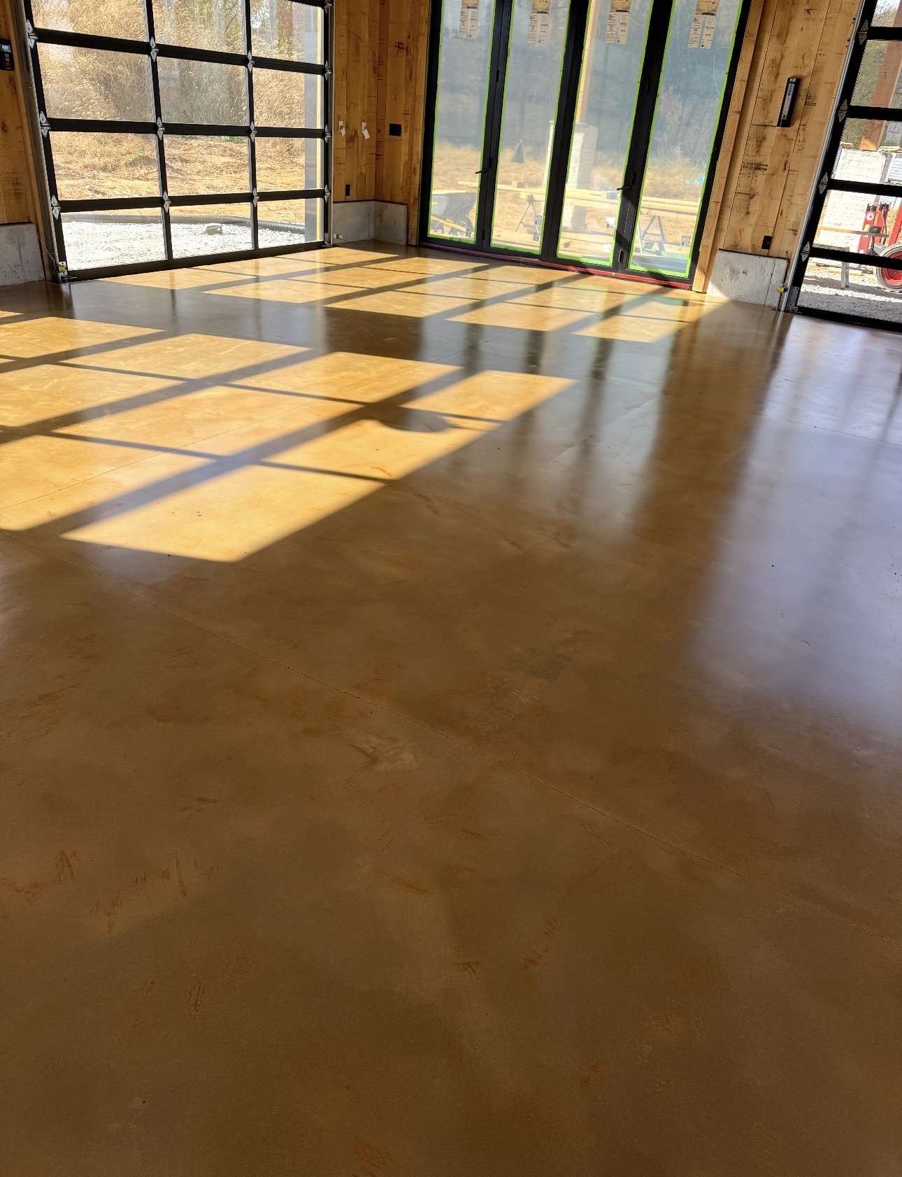 Amber stained and sealed concrete floor in a timber-framed building with glass overhead doors
