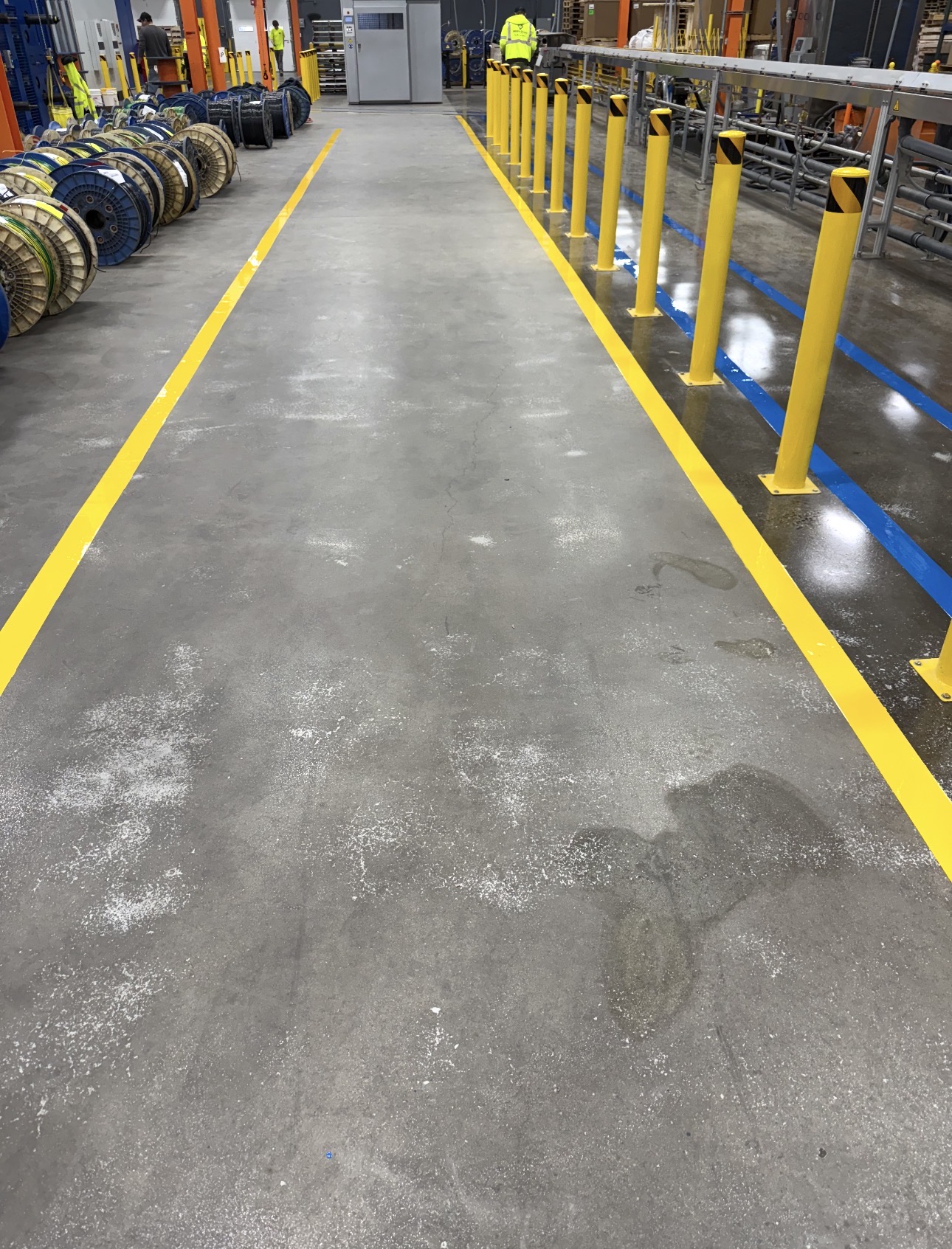 Industrial concrete floor with yellow safety lines and polished traffic lanes