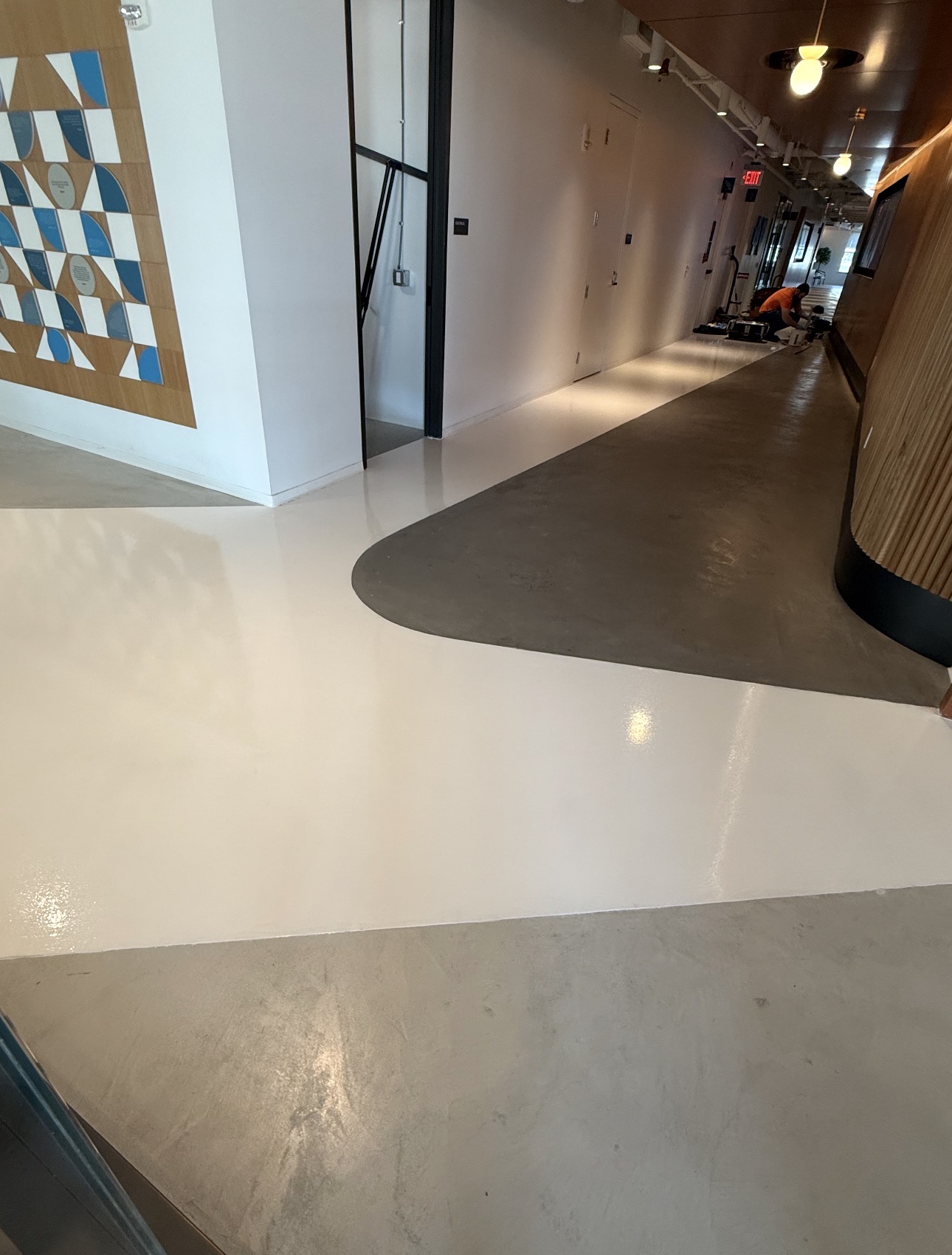 Multi-color solid epoxy flooring with curved white, gray, and dark sections in a commercial hallway