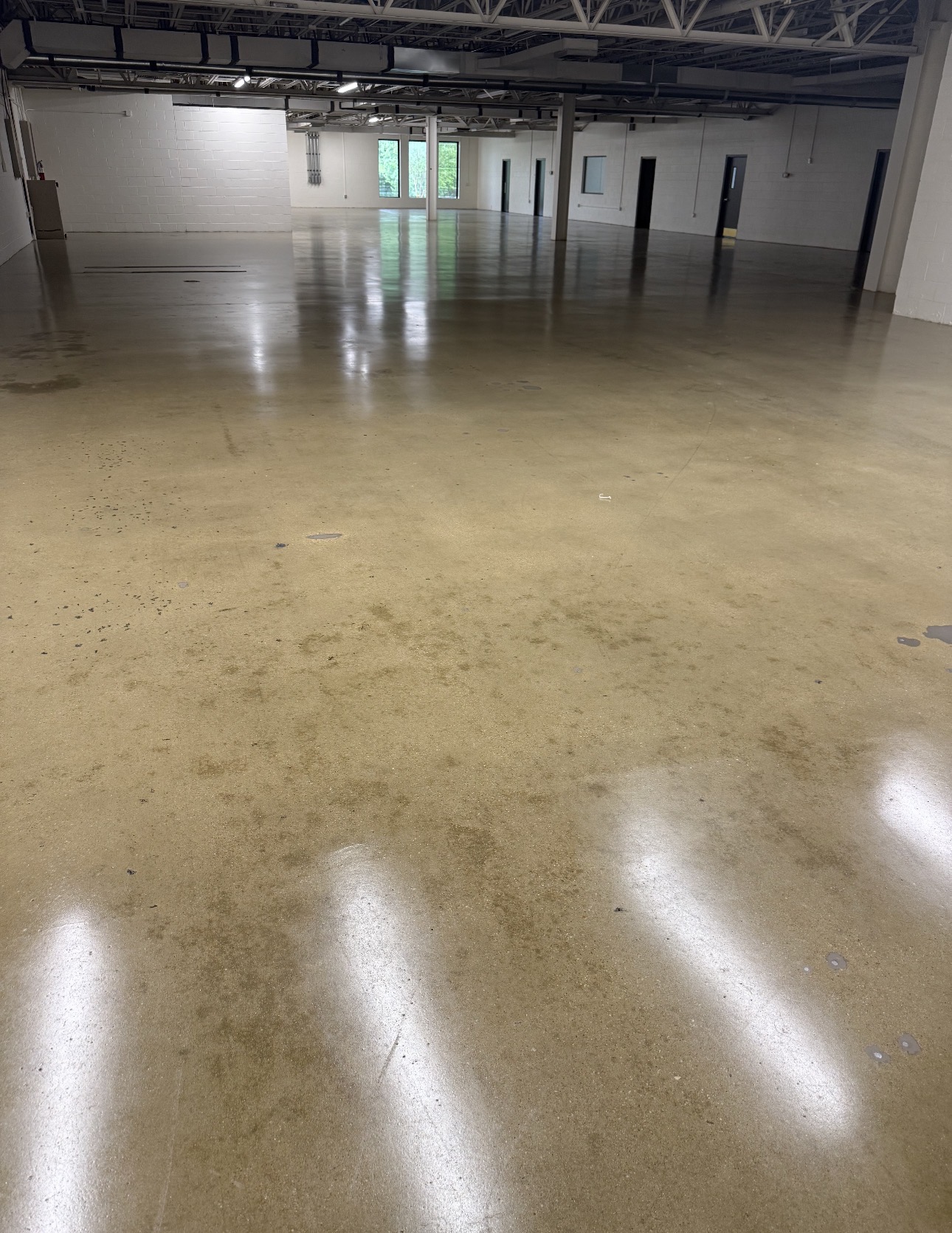 Large tan polished concrete warehouse floor reflecting overhead lighting