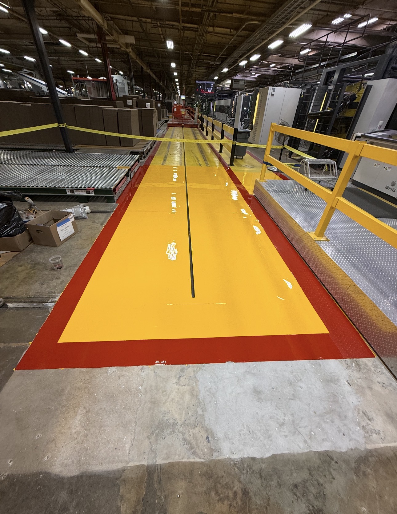 Yellow and red high performance coating marking a walkway in a factory