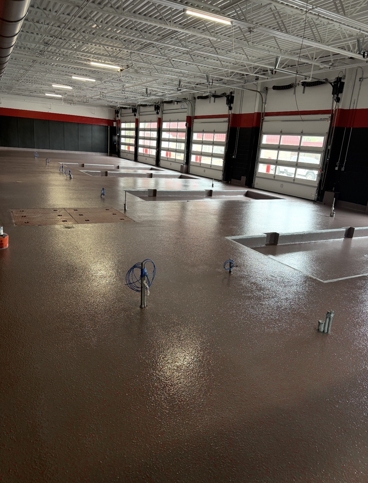 Red industrial floor coating installed across a large apparatus bay
