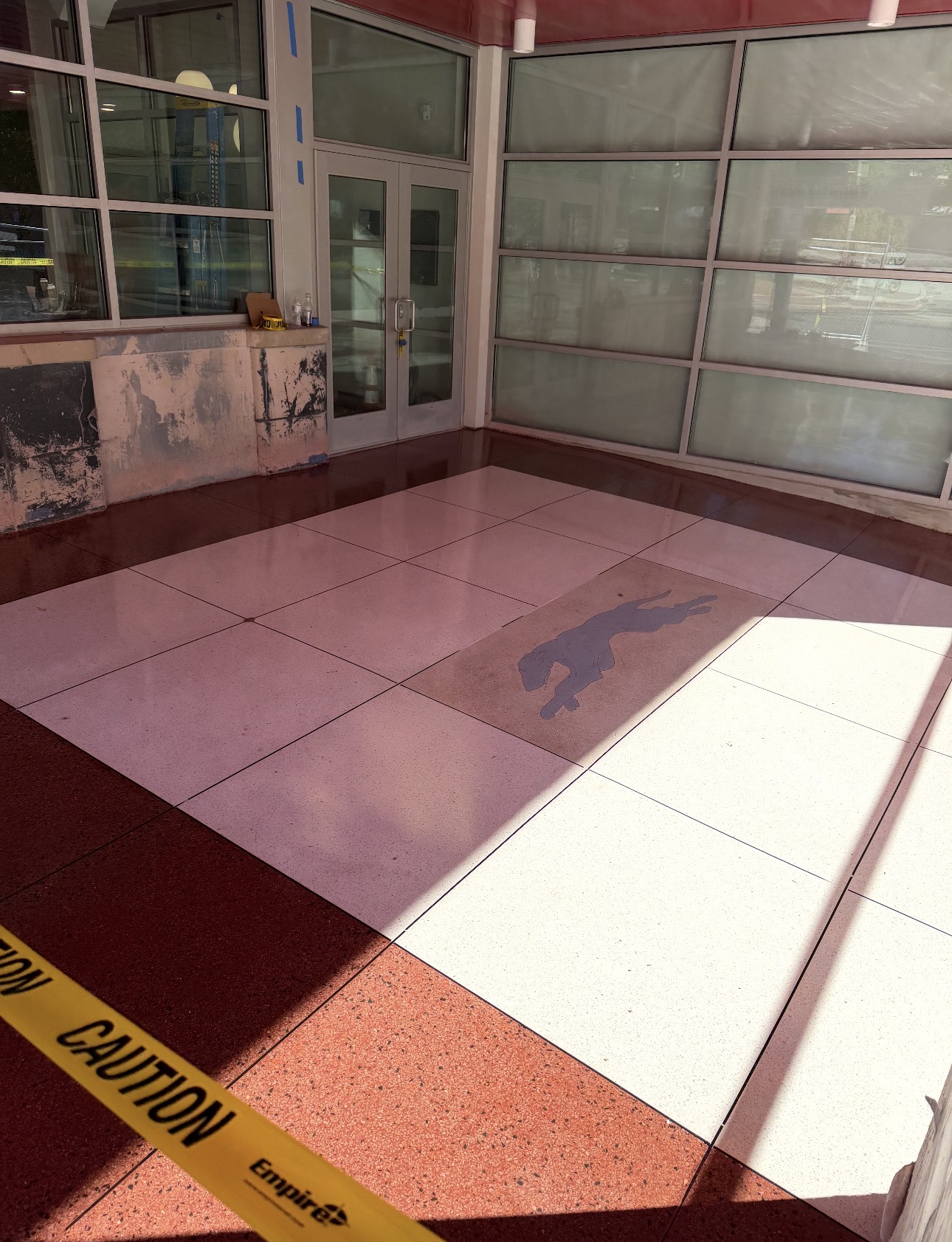 Restored terrazzo entry floor with contrasting border, grid, and inset logo