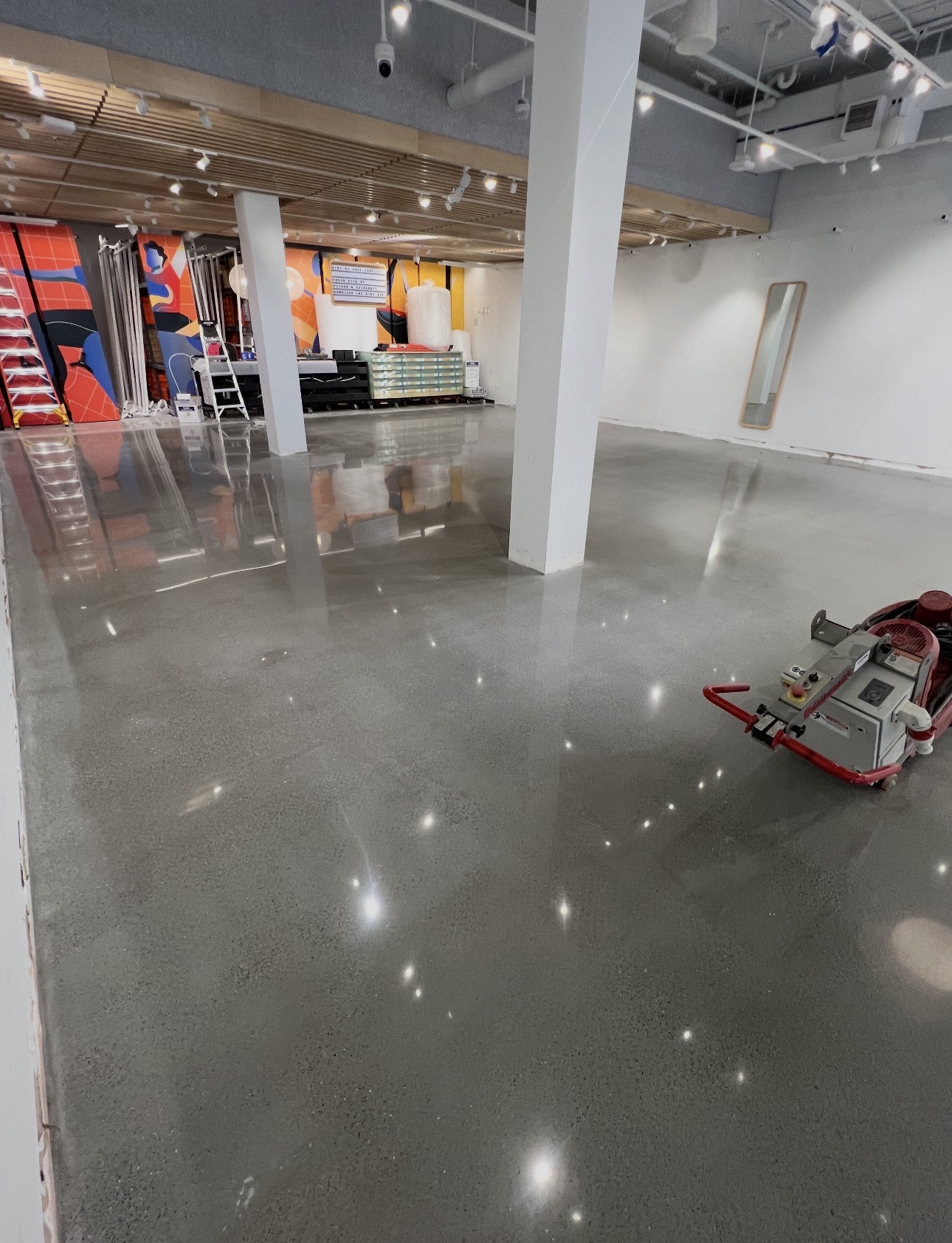 Gray polished concrete floor in a retail studio with a floor grinder on site