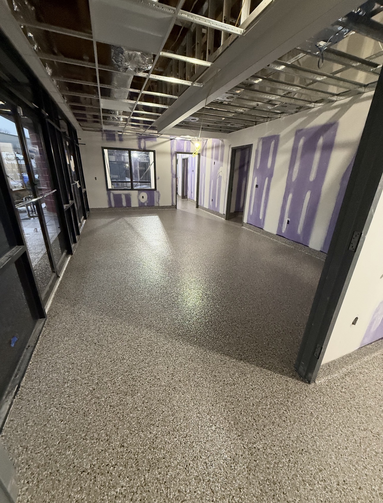 Gray flake epoxy flooring across a commercial room and connecting hallway